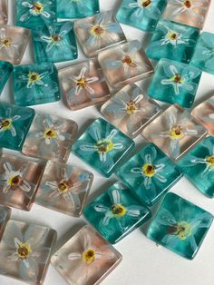 several square glass tiles with flowers painted on the sides and one flower in the middle