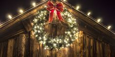 a christmas wreath on the side of a wooden building with lights hanging from it's sides