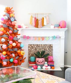 an orange christmas tree decorated with balloons and other decorations in front of a fire place