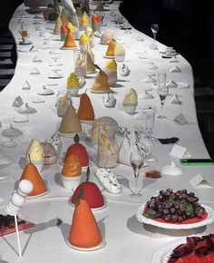 a long table with many different types of desserts and drinks on it, all arranged in the shape of cones