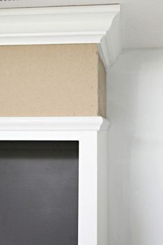 a cat is sitting on the ledge of a white bookcase in front of a blackboard