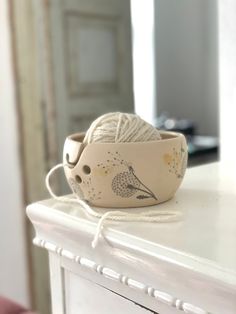 a bowl is sitting on top of a dresser with yarn in the shape of a bird