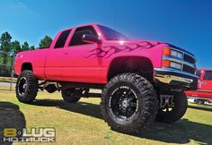 a bright pink truck with flames painted on it's front tires and rims