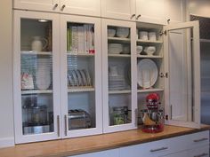 a kitchen with white cabinets and glass doors