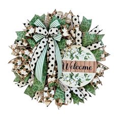 the welcome wreath is decorated with green and white flowers, polka dot ribbon, and a wooden sign