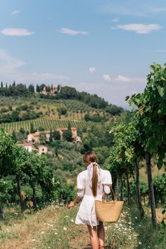 a woman walking down a path with a basket in her hand