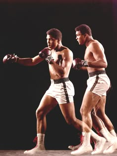 two men in shorts and boxing gloves are facing each other while one man is holding a punching glove