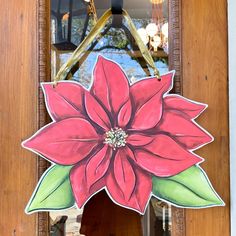 a large red flower painted on the side of a wooden door with a mirror behind it