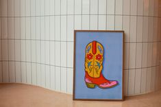 a painting of a cowboy's boot is on display in the corner of a tiled room