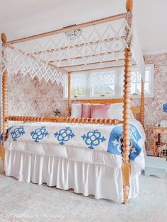 a four poster bed in a bedroom with pink and blue wallpaper