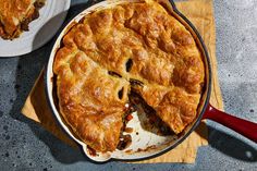 a pie sitting on top of a wooden cutting board next to a bowl of food