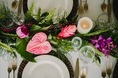 the table is set with plates, silverware and flowers