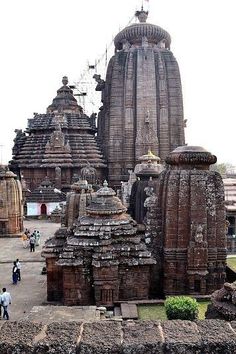 an old temple with many statues and people walking around it