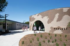 several people are walking around in front of a building that is made out of bricks