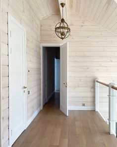 an empty room with wood paneling and a chandelier hanging from the ceiling