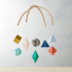 an origami mobile with geometric shapes hanging from it's wooden hangers