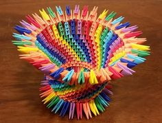 a multicolored vase made out of folded paper on top of a wooden table