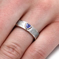 a woman's hand wearing a silver ring with a blue stone in the middle