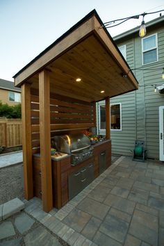 an outdoor kitchen is shown in front of a house with a grill on the outside