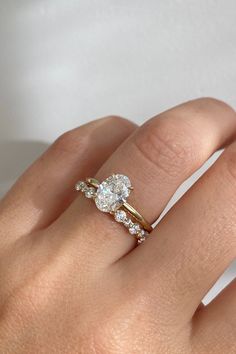 a woman's hand with a diamond ring on top of her finger and an engagement band