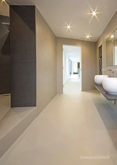 a modern bathroom with two sinks and large mirrors on the wall, along with stairs leading to another room