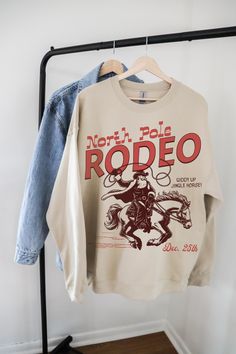 Get ready to jingle and yeehaw through the holidays with this fun and festive Western Christmas sweatshirt! Featuring a playful design of Santa riding a rearing horse, complete with the phrases "Up on the Rooftop" and "Yee Haw!" this cozy sweatshirt adds a quirky cowboy twist to holiday traditions. Perfect for Christmas parties, country-themed festivities, or anyone who loves a little humor with their holiday spirit, this sweatshirt makes a great gift for Western lovers and festive fashionistas Western Theme Christmas Party, Cowboy Christmas Party, Rearing Horse, Cowboy Christmas, Cute Shirt Designs, Western Rodeo, Yee Haw, Western Christmas, Cow Girl