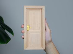 a person holding up a wooden door with a key on the front and back side