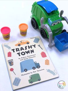 there is a toy truck next to some playdoughons and a book on the table