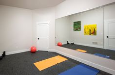 an exercise room with yoga mats on the floor and colorful balls in front of a mirror