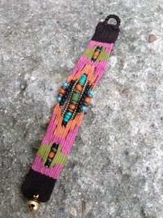 a bracelet with beads and bells is laying on the ground in front of a rock