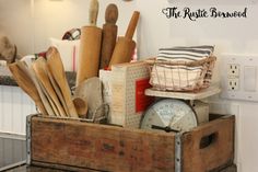 a wooden box filled with kitchen utensils on top of a counter next to a clock