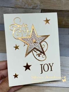 a hand holding up a card with gold foil stars on it and the word joy written in