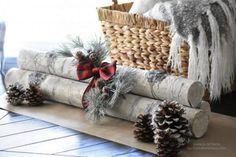 the log is decorated with pine cones and red ribbon for holiday decor on the table