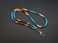 a blue, white and orange lanyard with a metal hook on a black surface