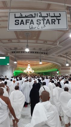 a large group of people dressed in white are walking through a building with a sign that says safa start