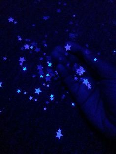 a hand is shown with blue stars on the dark ground in front of it, as if to be reaching for something