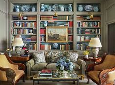 a living room filled with furniture and bookshelves covered in lots of bookcases