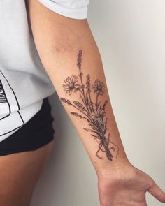 a woman's arm with flowers on it and her hand holding the wrist tattoo