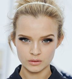 a close up of a person wearing a black shirt and a headband with pearls on it