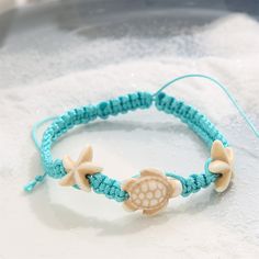 Bright blue anklet with beige sea creature accents. Adjustable sliding bead closure. 6.3" L with 4.33" extender Sliding bead closure turquoise / polyester Adjustable Blue Jewelry With Starfish Charm, Adjustable Blue Starfish Jewelry, Blue Starfish Charm Anklet For Vacation, Turquoise Beach Anklets With Starfish Charm, Blue Beaded Starfish Anklet, Adjustable White Starfish Anklets, Turquoise Anklets With Starfish Charm For Beach, Blue Anklet With Starfish Charm For Vacation, Adjustable Blue Bracelets With Starfish Charm