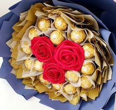 a bouquet of roses and chocolates in the shape of a heart on top of blue paper