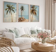 a living room filled with white furniture and paintings on the wall above it's windows