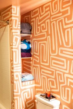 a bathroom with an orange wall and white toilet