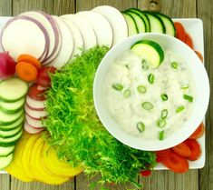 a white plate topped with cucumbers, carrots and celery next to sliced radishes