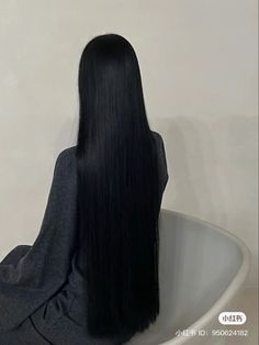 the back of a woman's head sitting in a bathtub with long black hair