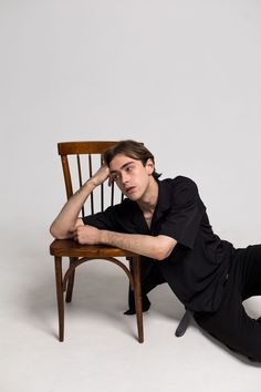 a man sitting on the floor next to a chair with his hand on his head