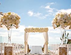 an outdoor wedding setup with white flowers and umbrellas