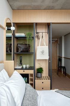 a bed sitting next to a wooden shelf filled with bags