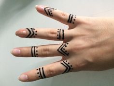 a woman's hand with three different tattoos on her fingers and one has an arrow