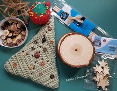 a crocheted christmas tree ornament next to a bowl of buttons and wood slices